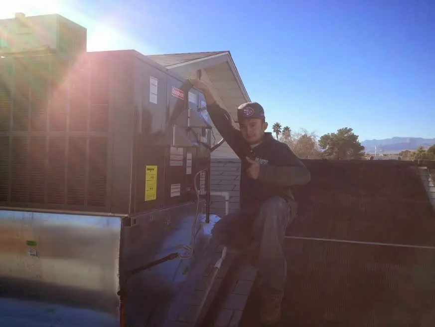 HVAC technician performing Air Duct Cleaning on a rooftop unit in Dixon
